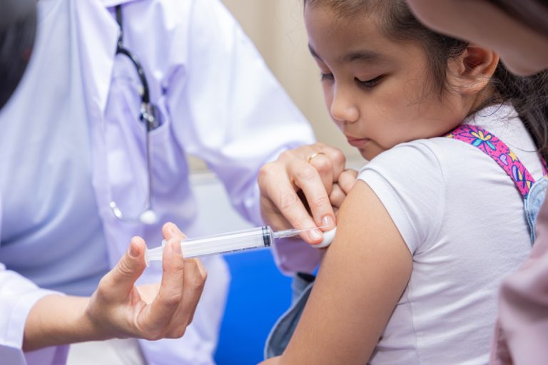 Young woman pediatrician performs a vaccination of a little girl